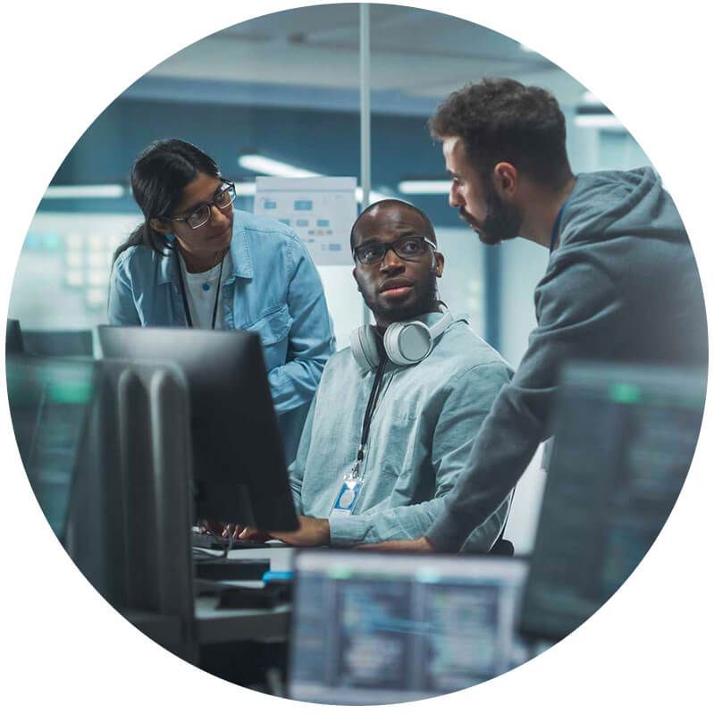 Three people discussing information around a computer